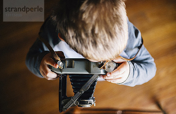 Draufsicht eines Jungen mit einer Oldtimer-Kamera