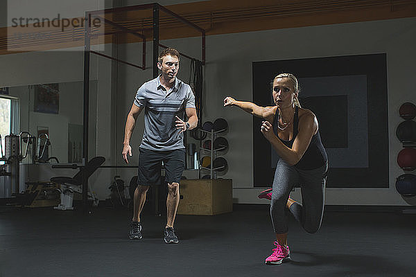 Trainer betrachtet weibliche Kunden beim Training im Fitnessstudio