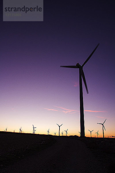 Windturbinen auf dem Feld gegen klaren Himmel bei Sonnenuntergang