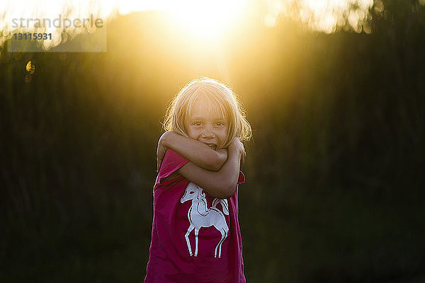 Porträt eines glücklichen Mädchens  das sich bei Sonnenuntergang umarmt