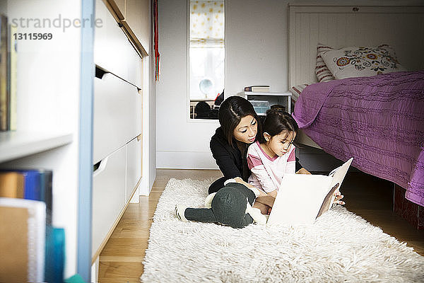 Mutter unterrichtet Tochter  während sie auf Teppich im Schlafzimmer sitzt