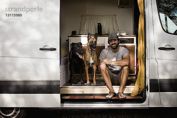 Porträt eines lächelnden Mannes  der mit Hunden im Wohnmobil sitzt