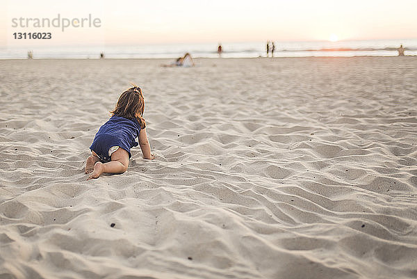 Kleines Mädchen in voller Länge auf Sand am Strand