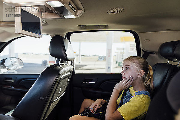 Mädchen  das im Auto sitzt und fernsieht