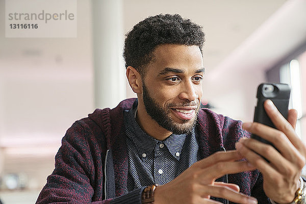 Geschäftsmann benutzt ein Smartphone  während er im Büro sitzt