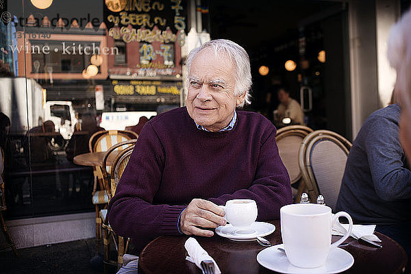 Nachdenklicher älterer Mann sitzt im Bürgersteig-Café