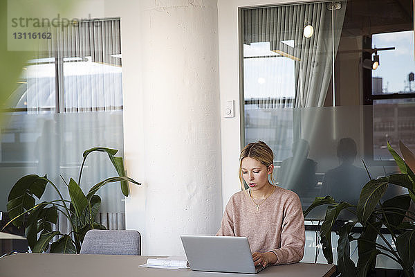 Geschäftsfrau benutzt Laptop-Computer am Tisch im Büro