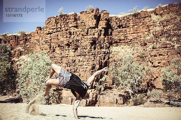 Mann tanzt auf Sand gegen Felsformationen in der Wüste
