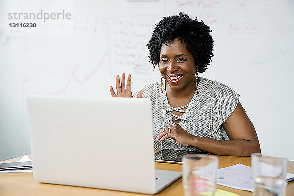 Lächelnde Geschäftsfrau benutzt Laptop-Computer  während sie im Sitzungssaal im Büro sitzt