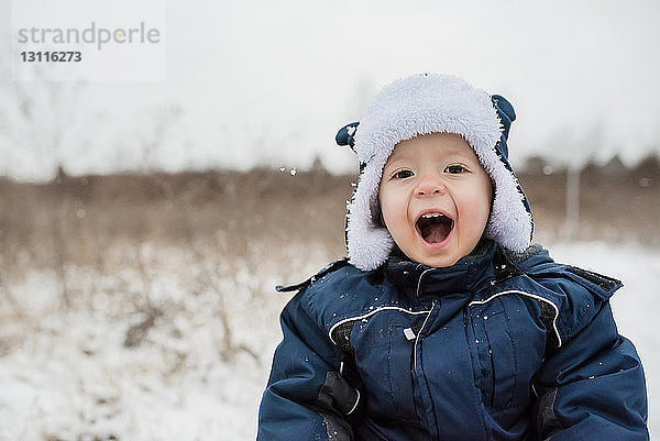 Porträt eines niedlichen verspielten Jungen  der im Winter in warmer Kleidung schreit