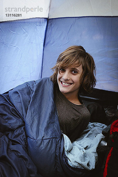 Porträt eines lächelnden Jungen  der sich im Zelt entspannt