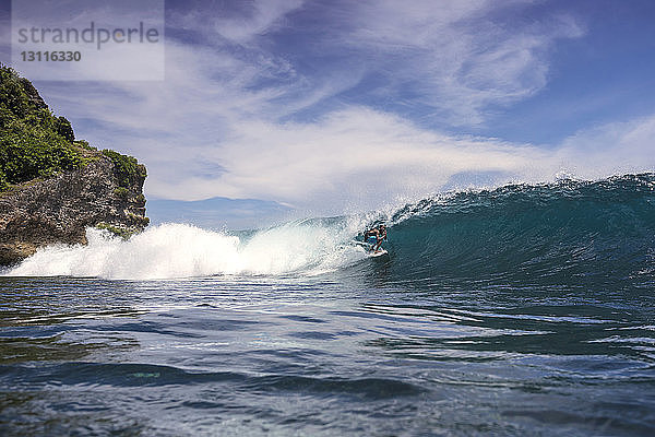 Mann surft auf dem Meer gegen den Himmel bei Bali