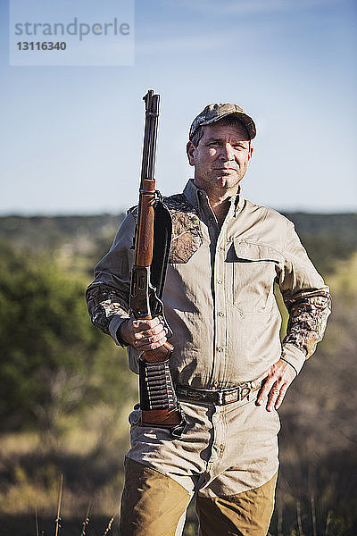 Porträt eines Jägers mit Gewehr in der Hand und gegen den Himmel stehend