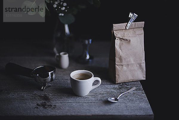 Espressotasse mit Papiertüte und Siebträger auf Holztisch