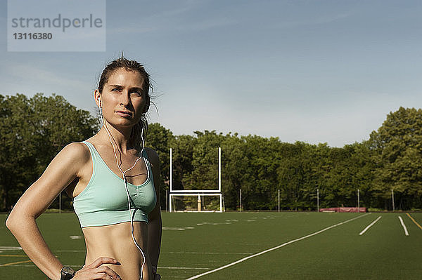 Sportlerin  die Musik hört  während sie auf dem Sportplatz steht