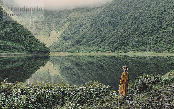 Rückansicht einer Frau  die am Seeufer im Wald steht