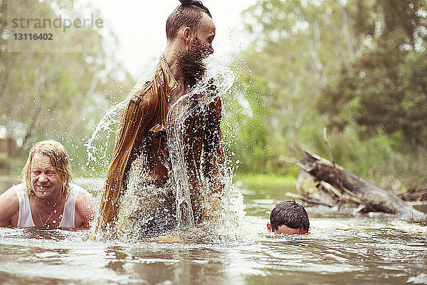 Glückliche Freunde beim Baden im Fluss im Wald