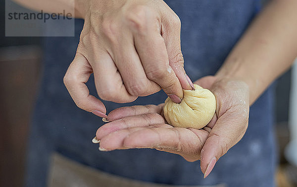 Mittelteil einer Frau  die zu Hause einen Teigball macht