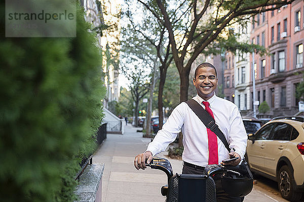 Porträt eines glücklichen Geschäftsmannes  der mit dem Fahrrad auf einem Fußweg steht