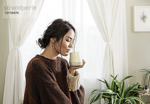 Junge Frau trinkt zu Hause Kaffee