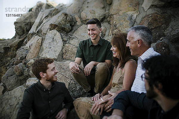 Glückliche Eltern unterhalten sich mit ihren Söhnen  während sie bei Felsformationen im Park sitzen