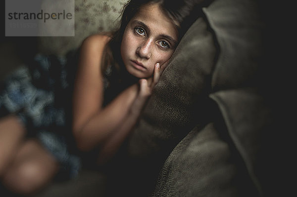 Hochwinkelporträt eines traurigen Mädchens auf dem Sofa sitzend