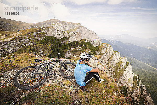Hochwinkelaufnahme eines Mannes  der mit dem Fahrrad auf einem Berg sitzt