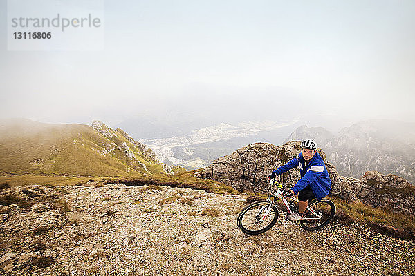 Hochwinkelansicht eines Athleten  der Fahrrad fährt  auf einem Berg gegen den Himmel