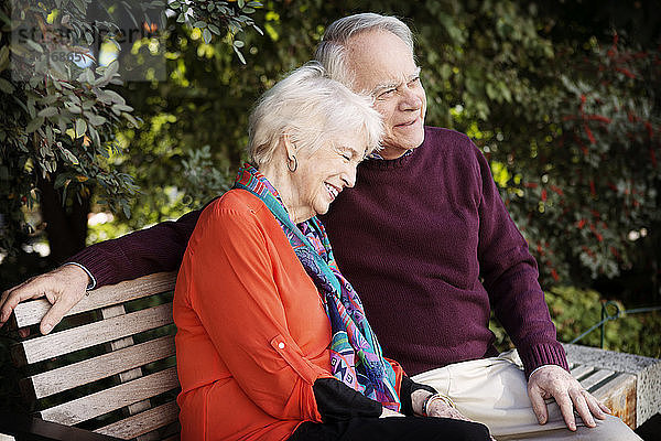 Glückliches älteres Ehepaar sitzt auf Parkbank