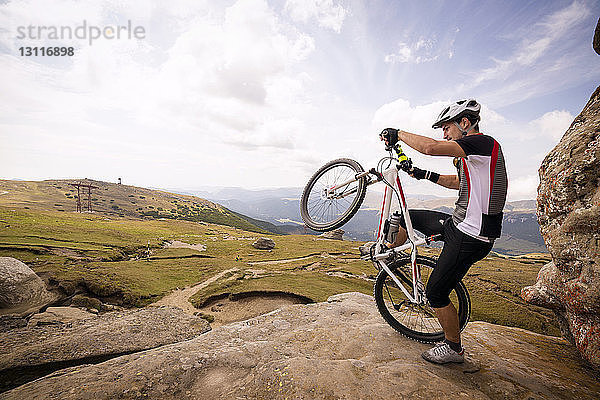 Mann mit Wheelie auf Berg gegen Himmel