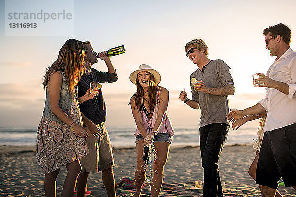 Glückliche Freunde genießen Drinks am Strand