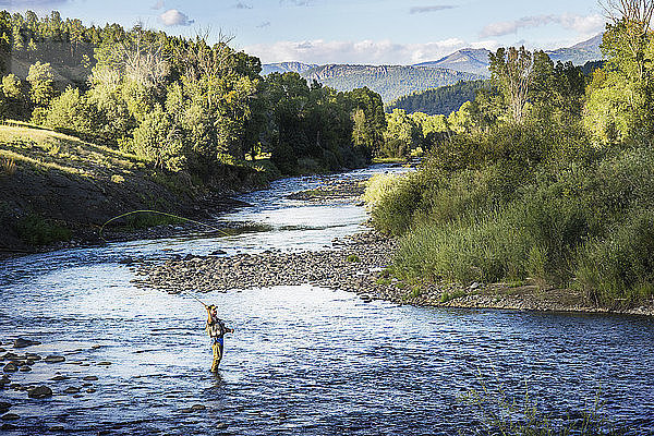 Mann fischt im Fluss inmitten der Felder