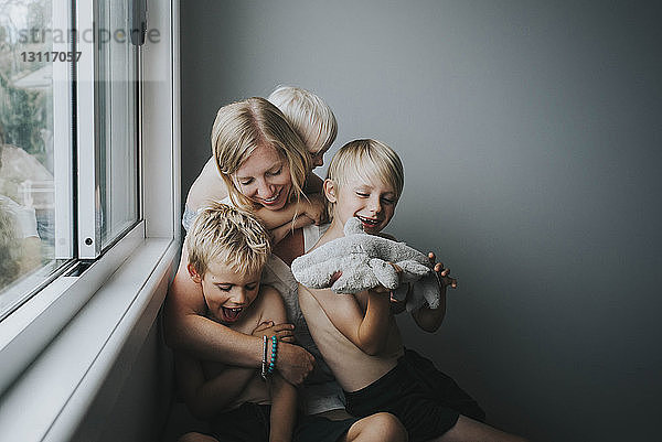 Glückliche Mutter mit Kindern  die zu Hause am Fenster sitzen