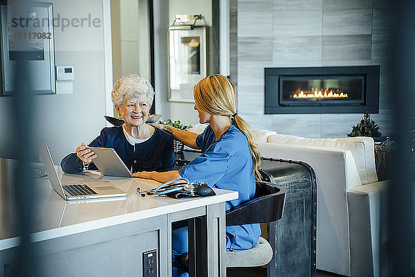 Ältere Frau mit Tablet-Computer und häuslicher Pflegekraft
