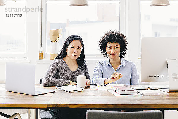 Porträt selbstbewusster Geschäftsfrauen  die am Schreibtisch im Büro arbeiten