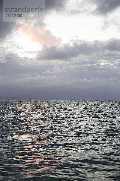 Szenische Ansicht des Meeres vor bewölktem Himmel bei Sonnenuntergang
