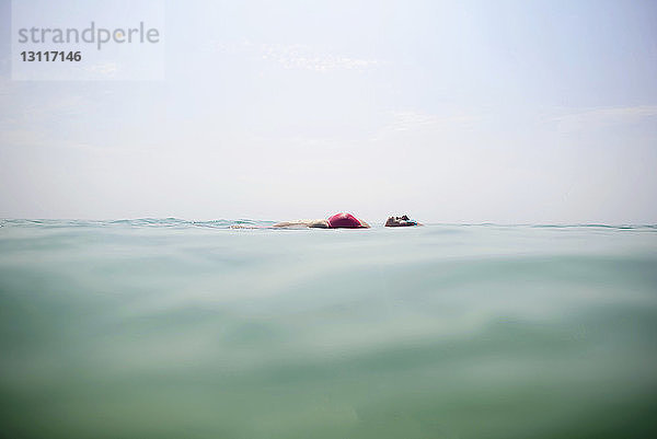 Frau schwimmt im Meer gegen den Himmel