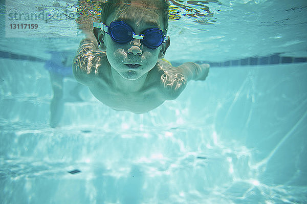 Junge ohne Hemd schwimmt unter Wasser im Pool