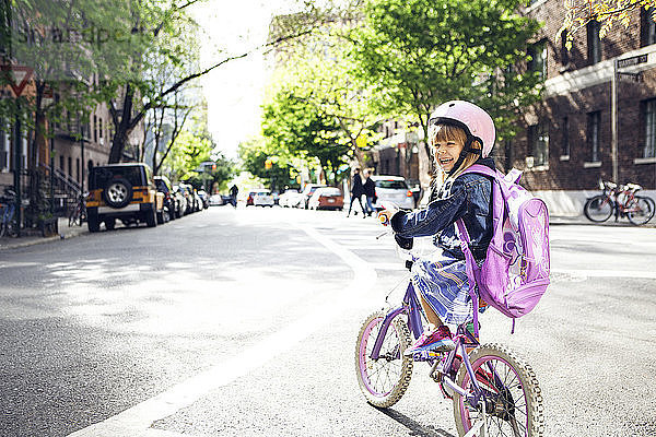Seitenansicht eines glücklichen Mädchens beim Fahrradfahren auf der Straße
