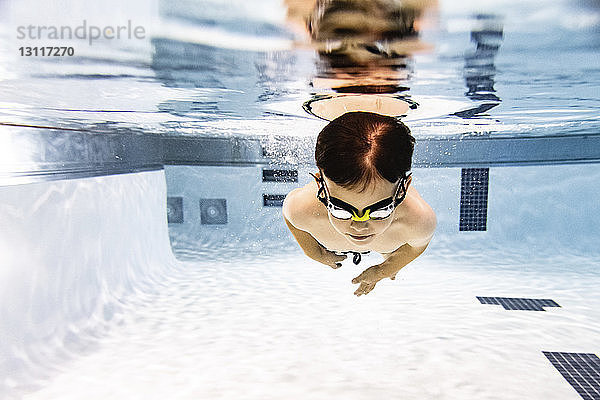 Junge ohne Hemd schwimmt unter Wasser im Pool