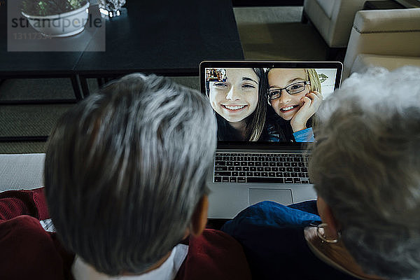 Hochwinkelansicht der Videokonferenz der Großeltern mit den Enkelinnen über Laptop-Computer zu Hause