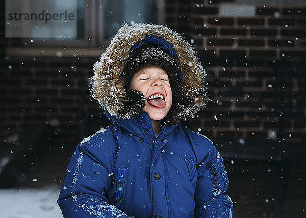 Fröhlicher Junge geniesst Schneefall
