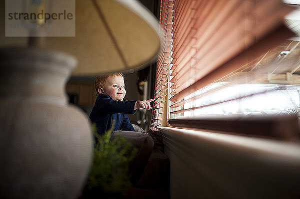 Kleiner Junge spielt zu Hause mit Fensterläden