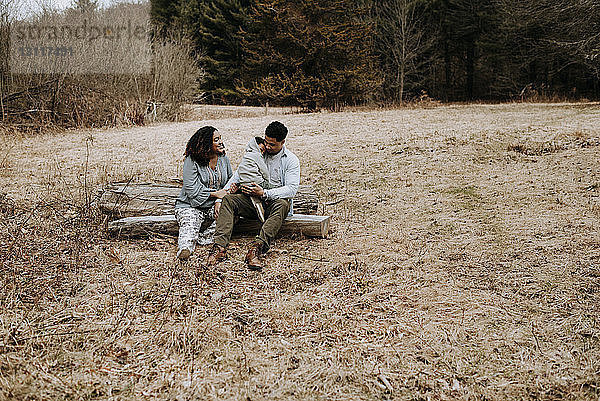 Ehepaar redet  während es mit seinem Sohn auf einem Baumstamm im Wald sitzt