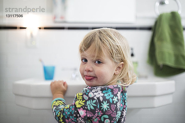 Porträt eines kleinen Mädchens am Waschbecken im Badezimmer