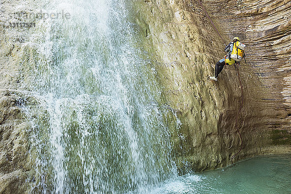 Frau besteigt Berg am Wasserfall