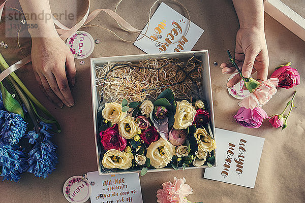 Draufsicht eines Floristen  der Blumen in einer Kiste auf dem Tisch im Blumenladen arrangiert