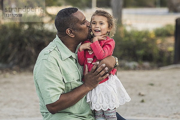 Vater küsst Tochter auf Spielplatz