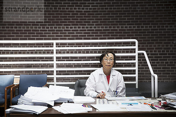 Porträt einer leitenden Wissenschaftlerin am Schreibtisch sitzend mit Dokumenten