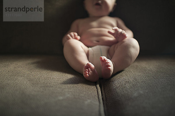 Unterer Teil eines Jungen  der zu Hause auf dem Sofa sitzt